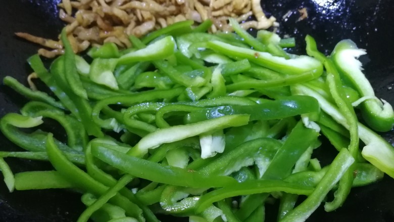 青椒炒肉丝,把肉丝推到锅边,放入青椒。