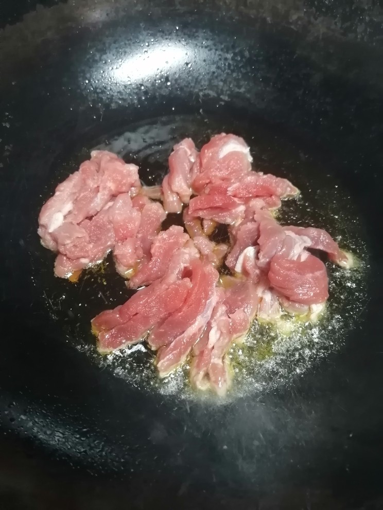 小炒黄牛肉,开火加热锅倒入油,倒入牛肉丝翻炒至六分熟。