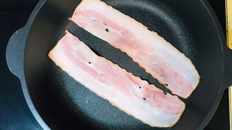 培根鸡蛋饼,起油锅,将培根码放进锅里,转慢火,煎一下培根