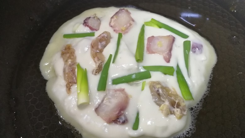 海鲜蛋饼,放上剩下的海鲜块儿和葱段,饼面点少许油。