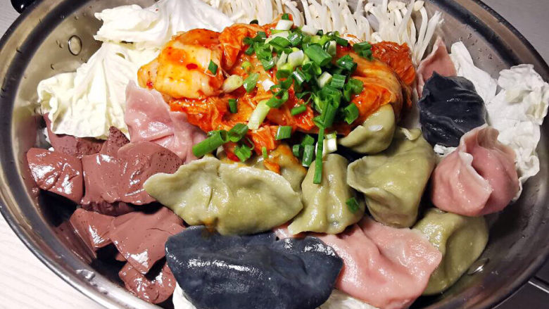 部队火锅,白菜上面码上金针菇,鸭血,水饺,中间放韩式泡菜,端上桌再加入鸡高汤,煮开即可