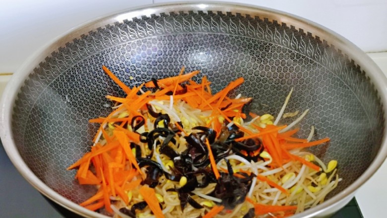 爆炒绿豆芽,再加入切好的胡萝卜丝与黑木耳丝,加入半小碗纯净水。