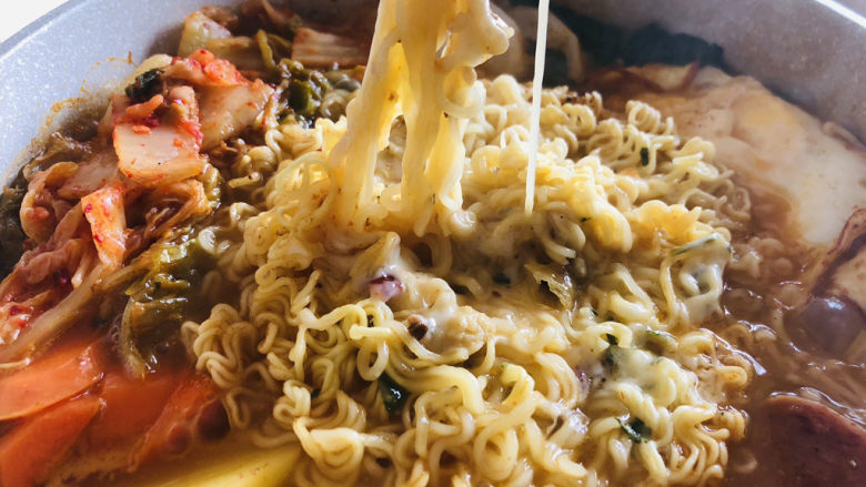 部队火锅,待所有蔬菜完全煮熟后关火,用筷子挑起面条芝士可以拉出细丝。