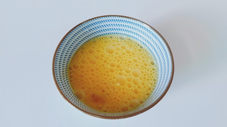 洋葱炒蛋,鸡蛋加一点点料酒,用筷子给打散。