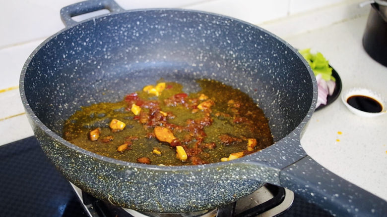 西芹炒鱿鱼,不粘锅中倒入适量食用油,倒入蒜瓣炒香,再放入<a style='color:red;display:inline-block;' href='/shicai/ 46964'>郫县豆瓣酱</a>炒出红油。