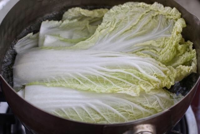 白菜包肉,白菜叶洗净后放进开水锅中,焯烫两分钟至菜叶变软,捞出沥水备用。