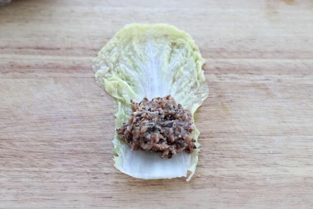 白菜包肉,先将白菜叶铺平,然后在靠近白菜帮的位置放适量肉馅。