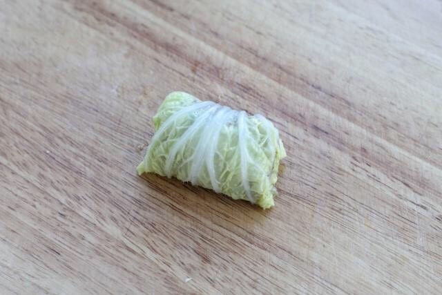 白菜包肉,由下至上慢慢卷起来,收口朝下放置,两边的菜叶往里收一收,将肉馅包裹住。
