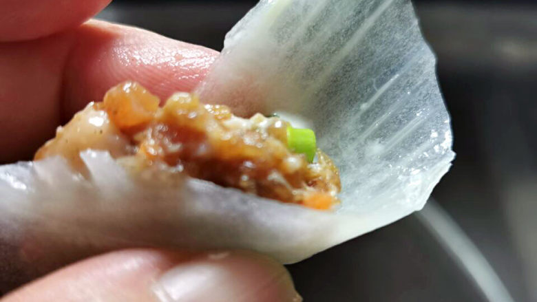 白菜包肉,取一片白菜,放入一小搓肉馅,一端捏紧,成了一头尖一头大的花瓣,放入蒸盘中,依序码成一朵盛开的花形