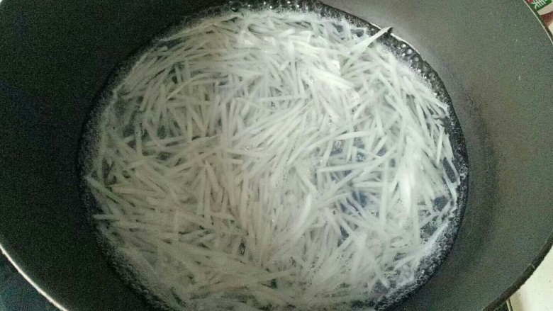 自制虾滑,锅中加入适量清水烧开加入萝卜丝焯水15秒,捞出沥干水份备用