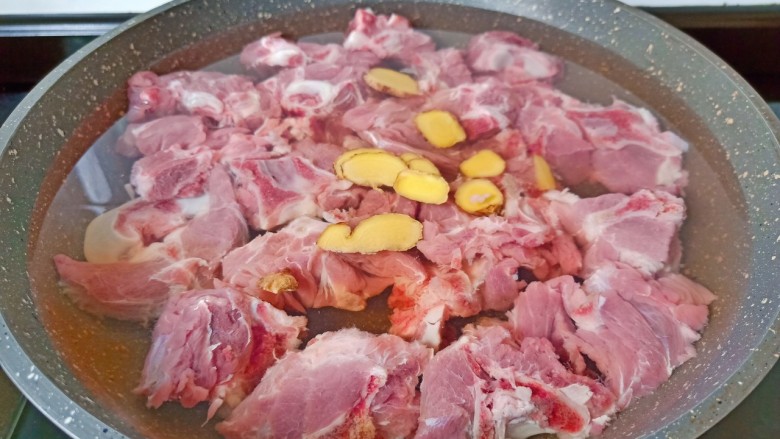 红烧羊蝎子,把洗净的羊蝎子放入冷水中,加上生姜片与料酒开大火煮开。