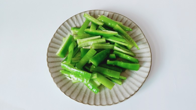 青椒炒豆干,青椒去籽对半切开,然后切成条形状。