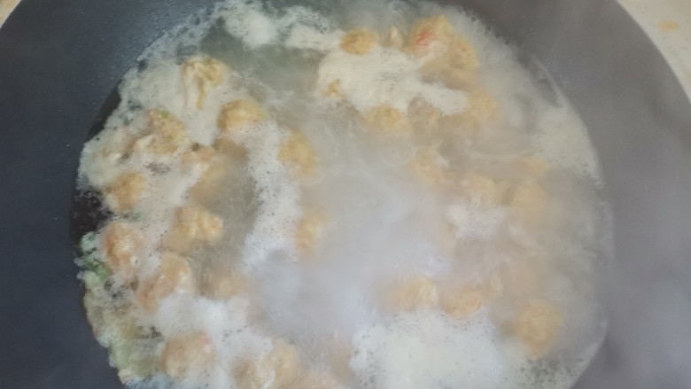 自制虾滑,水烧开,用虎口挤出虾丸,另外一个手用勺子挖起来放入锅中煮