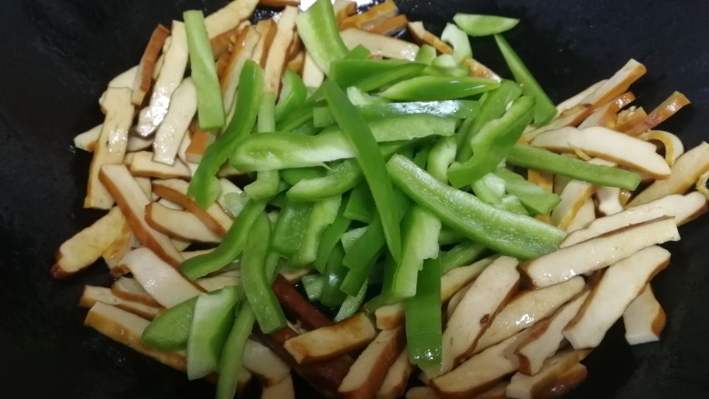 青椒炒豆干,放入青椒,文火翻炒均匀。