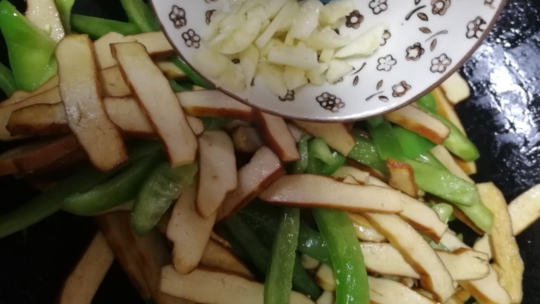 青椒炒豆干,加蒜末,文火翻炒均匀。