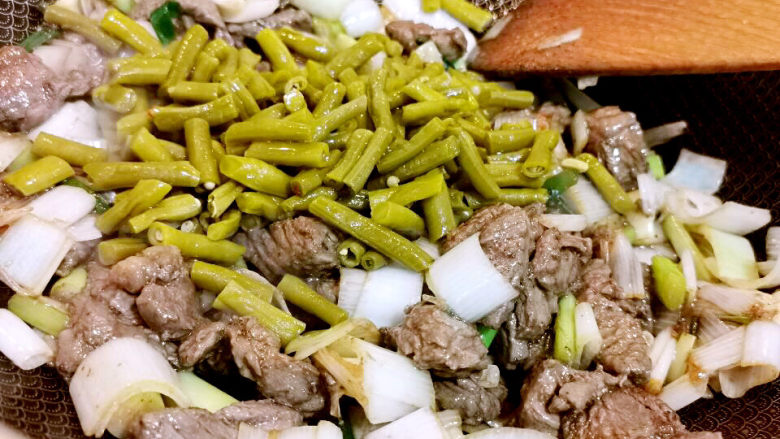 酸豆角炒牛肉,加入酸豆角一起翻炒一下,红椒加进来拌匀即可