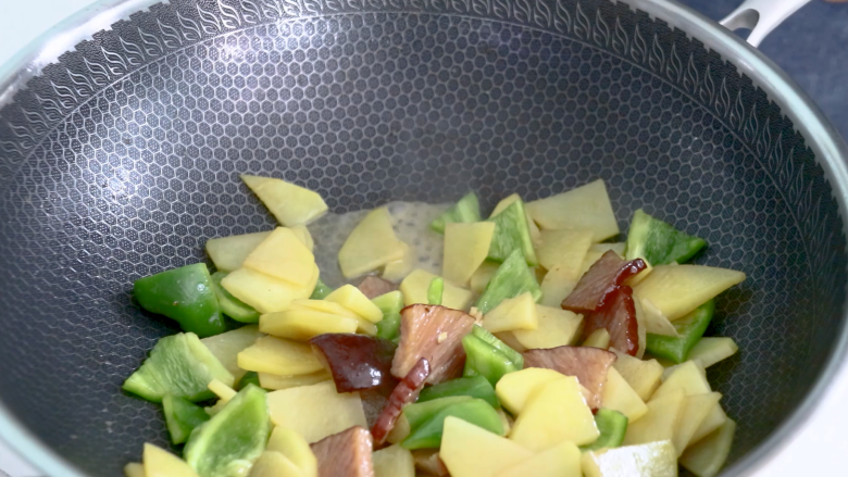 土豆片炒腊肉,倒入少许清水,防止糊锅