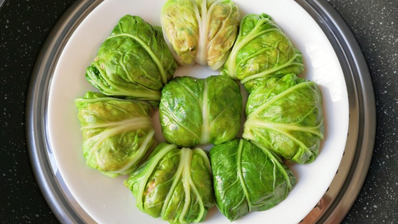 白菜包肉,包好的白菜包放入盘子里,锅里放水烧开,放入白菜包,再次烧开以后转中火蒸13分钟关火。