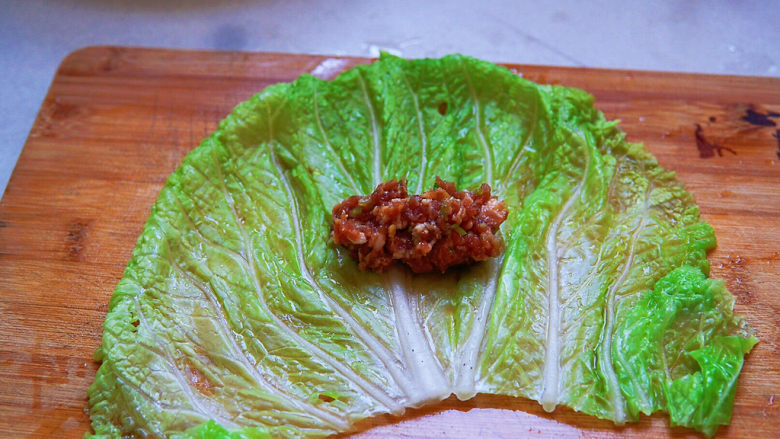 白菜包肉,将白菜叶铺平在案板上,肉馅放入白菜叶中间