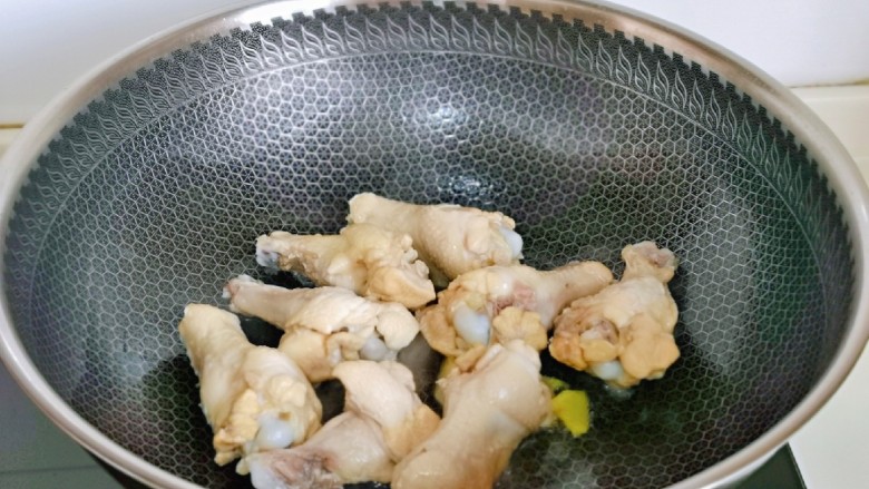 鸡腿炖蘑菇,起油锅,加入姜片煸炒,再加入鸡翅根煎至微黄。