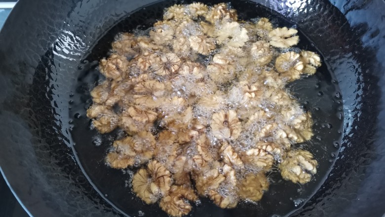 琥珀核桃,油温五成热倒入裹好糖分的核桃,小火慢炸(利用油的温度使核桃上的糖份凝固)