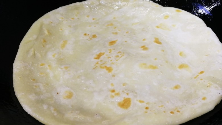 家常烫面饼,加适量食用油,铲子转一下饼,让底部和油接触,中小火烙15秒,饼微微起鼓。