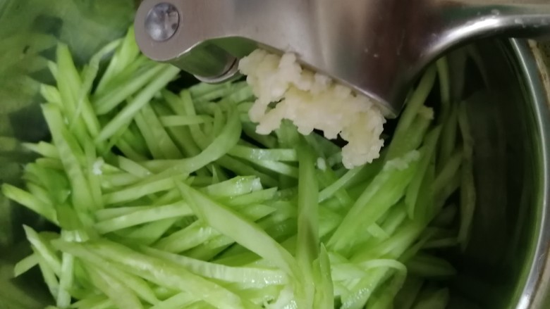 炝拌三丝,海带丝和黄瓜丝放入一个大碗里,2瓣蒜压成蒜蓉。