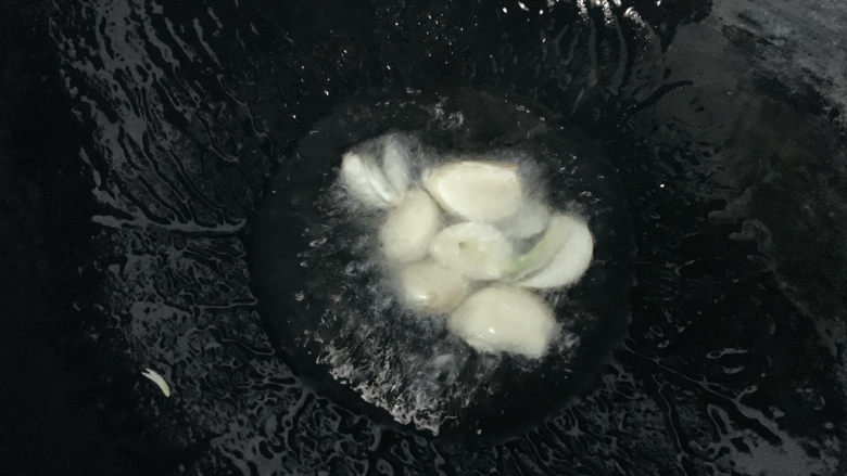 牙签羊肉,加入蒜瓣炸出香味,同时可以防止一会儿羊肉粘连。