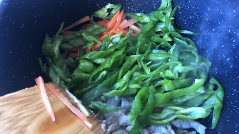 青椒肉丝面,接着放入青椒和胡萝卜,翻炒均匀断生。