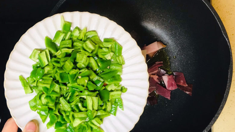 尖椒炒腊肉,投入尖椒块,煸炒均匀