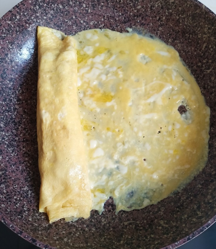 秋葵厚蛋烧,最后把剩余所有的蛋液沿着秋葵卷都倒进锅里,再卷起来。