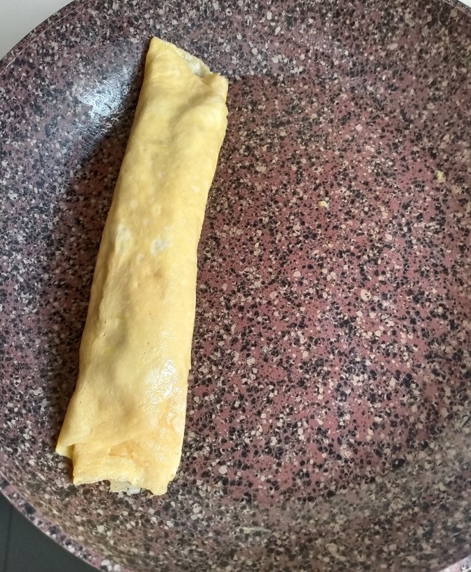 秋葵厚蛋烧,待表面带干不干的时候把秋葵卷往另一端卷起,如图