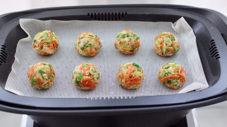 包菜虾皮菜团子,用手搓成大小一致的小团子，放入复式蒸屉中。