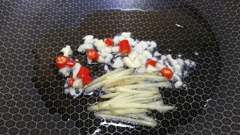 水煮千张,热锅凉油,放入姜丝,一半蒜末和小米辣,文火炒出香味。