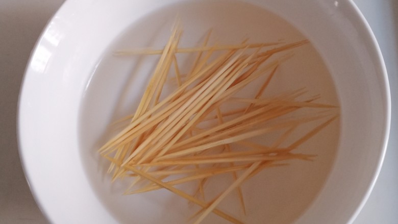 牙签羊肉,找一个碗,倒入温水或者热水,放入牙签,泡半个小时到一个小时。提前泡牙签可以在后续炸肉的时候避免黑糊