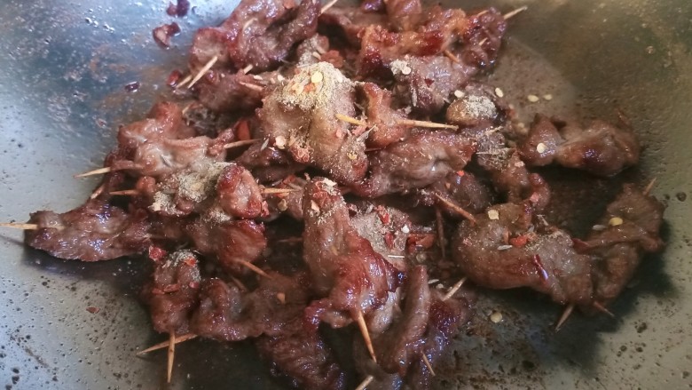 牙签羊肉,锅里留一点点底油,放入之前调匀的孜然辣椒料,炒几下炒出香味,倒入羊肉,翻炒均匀。