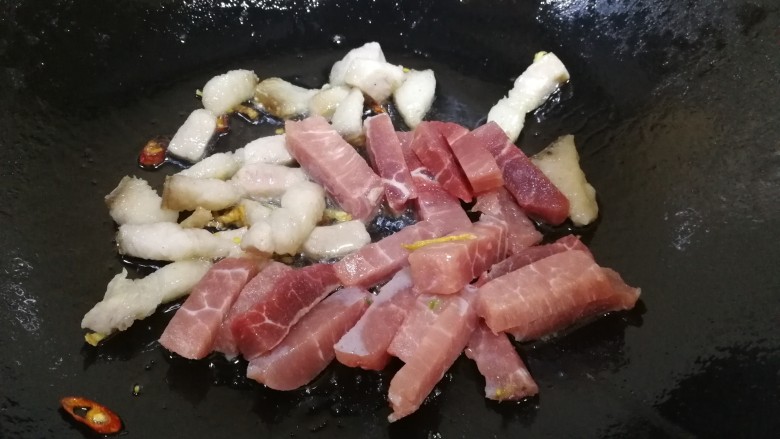 油豆腐烧肉,先放入肥肉,文火煸炒出油脂,再放入瘦肉条,文火翻炒。