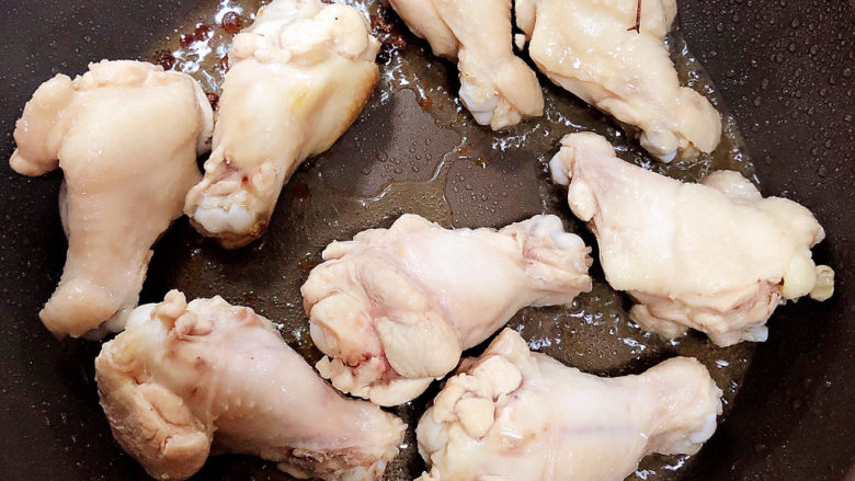 油豆腐烧肉,待白糖融化放入鸡翅根,翻炒均匀。