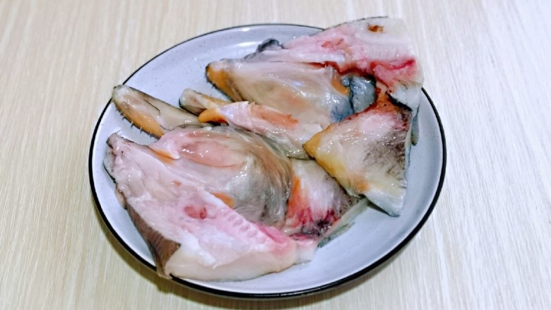 清蒸鸦片鱼,鱼头从中间剪开,一剪二,肉朝上放入盘中。