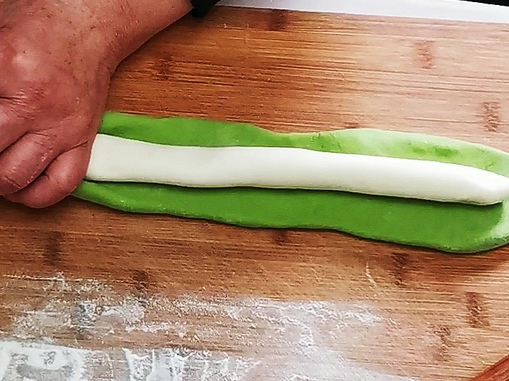 翡翠白菜饺子,江松,吃好的绿色面团和和白色面团分别搓成长条,将绿色的面团搓成条之后,压扁包入白色的面团
