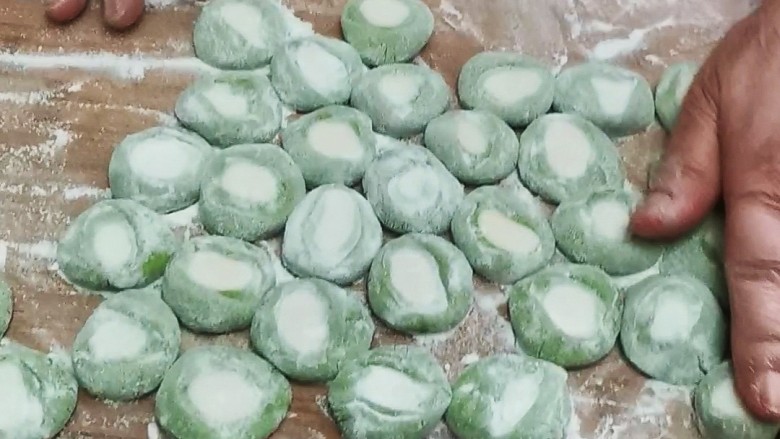 翡翠白菜饺子,撒上干面粉,防止粘连,竖起来,用手掌心压扁