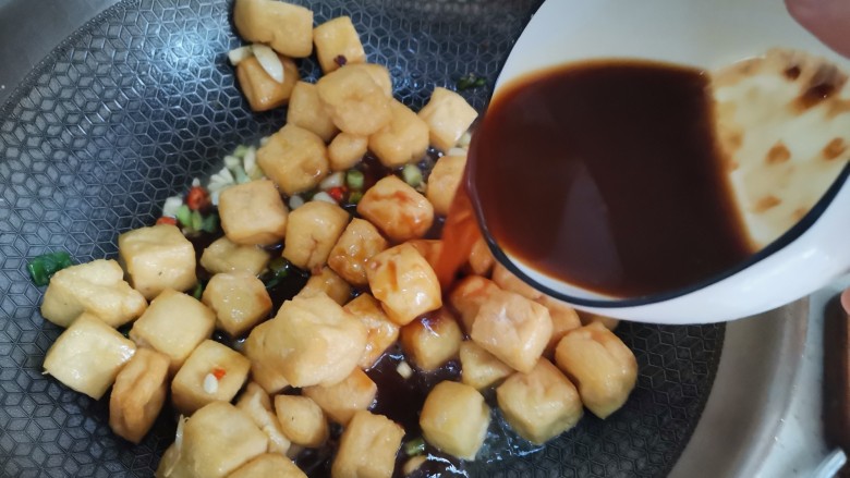 红烧油豆腐,倒入调好的料汁翻炒均匀,加入适量水炖几分钟