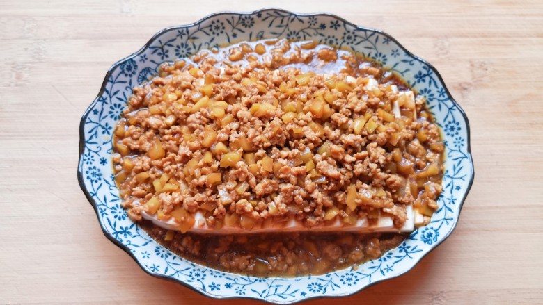榨菜肉末蒸豆腐,蒸过的豆腐取出,倒掉多余的水分,将炒好的肉末榨菜带汤汁一起浇在豆腐上面。