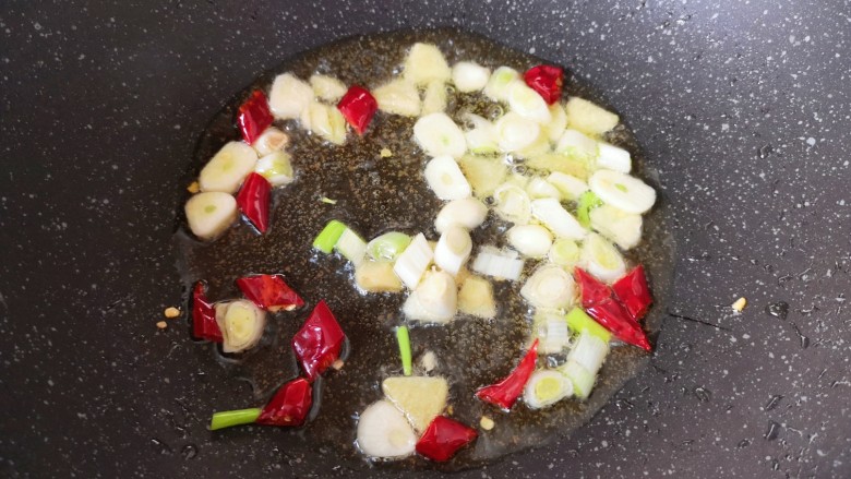红烧油豆腐,炒锅内倒适量的食用油烧热,下入葱姜蒜和干红辣椒炒香。
