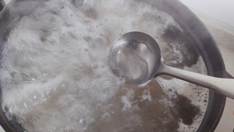 黄豆猪脚汤,铸铁锅搁置炉火上,大火开煮,煮开之后撇去浮沫