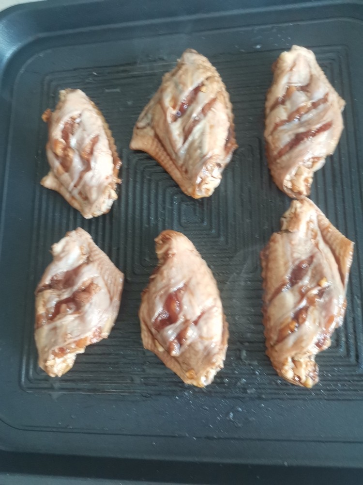 电饼铛蒜香烤翅,放入腌好的鸡翅,盖上盖子上下火180度烤3分钟