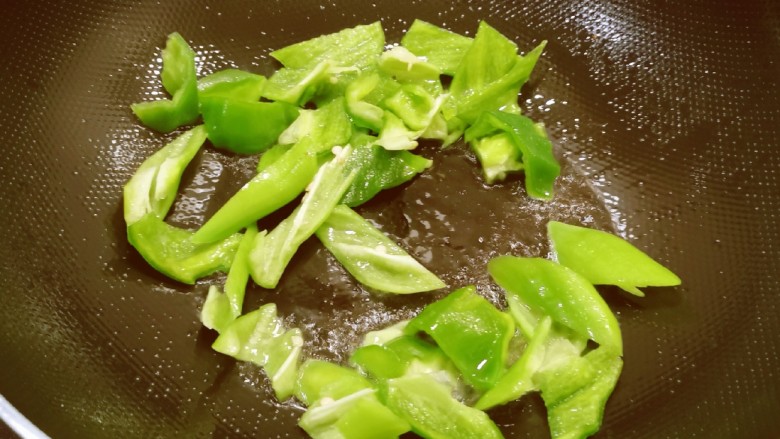 青椒炒杏鲍菇,起油锅放入一汤匙食用油,油热后放入青椒翻炒断生后出锅备用。
