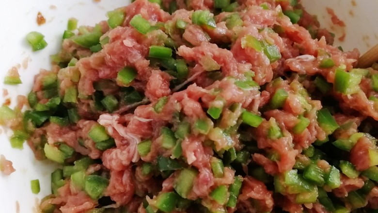 青椒肉包,放入青椒粒,加一小勺半的盐,搅拌均匀上劲。