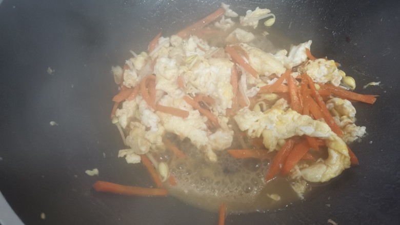 炒合菜,加入少量的清水,至胡萝卜和黄豆芽炒烂,加入鸡蛋。