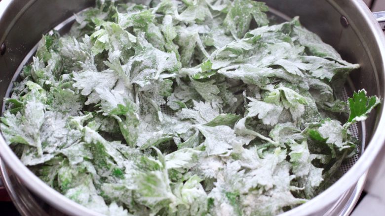 粉蒸芹菜叶,锅中倒入适量的清水烧开后,把搅拌均匀的芹菜叶放入锅中。